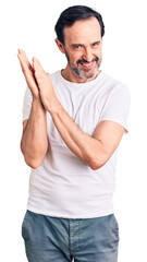 Naklejka premium Middle age handsome man wearing casual t-shirt clapping and applauding happy and joyful, smiling proud hands together