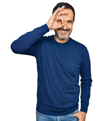 Middle age hispanic man wearing casual clothes doing ok gesture with hand smiling, eye looking through fingers with happy face.