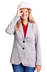 Beautiful young woman wearing architect hardhat doing ok gesture with hand smiling, eye looking through fingers with happy face.