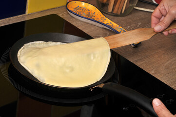Retourner une crêpe d'une crépière avec une spatule en bois en gros plan