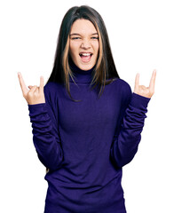 Young brunette girl with long hair wearing turtleneck sweater shouting with crazy expression doing...