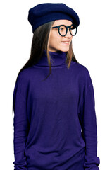 Young brunette girl with long hair wearing french look with beret and glasses looking away to side with smile on face, natural expression. laughing confident.