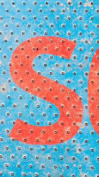 Letra S pintadas rojas en suelo met&aacute;lico perforado azul