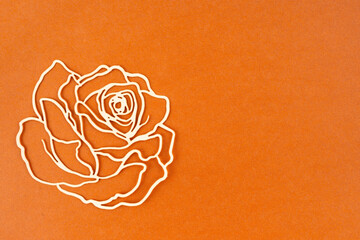Carve of white paper rose on a orange colour cardboard background.