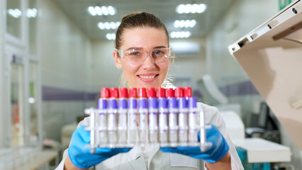 A scientist holds in his hands scientific laboratory test tubes for blood analysis. Clinic doctor, medical technician conducts laboratory testing of blood samples.