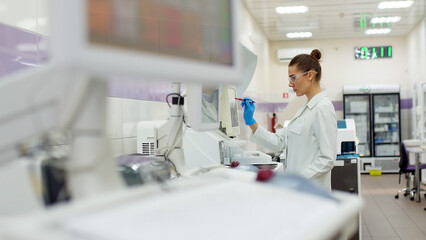 Fototapeta na wymiar A female scientist controls the operation of devices for laboratory research. Modern laboratory technologies. Medical research centrifuge.
