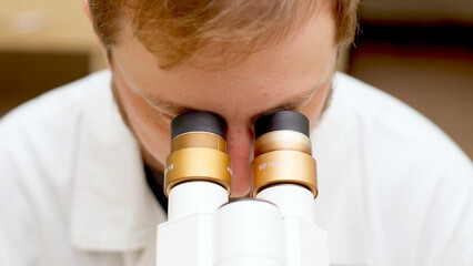 A medical scientist conducts experiments with DNA under a microscope in a biological laboratory....