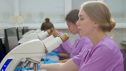 A team of scientists in a modern laboratory conducts research using a microscope.