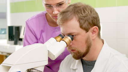A team of scientists in a modern laboratory conducts research using a microscope.