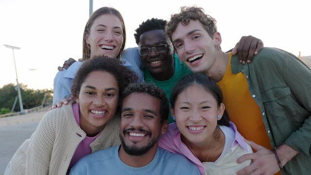 Portrait group of happy young gen z friends smiling at camera outdoor. Millennial diverse people relaxing together over urban background. Friendship and youth lifestyle concept.