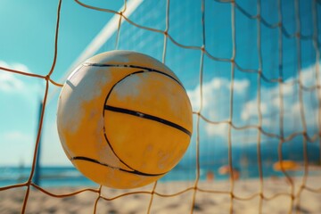 A yellow ball sits on top of a beach next to a net. Perfect for summer fun and beach activities