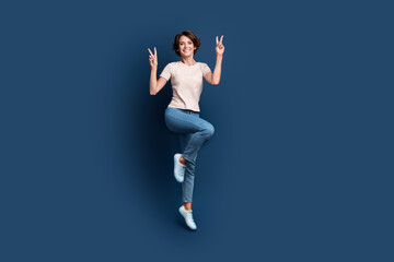Full body photo of pretty young girl jump show double v-sign wear trendy white clothes isolated on dark blue color background