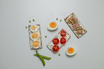 Ingredients for sandwich with boiled egg, cherry tomatoes, canned tuna, garlic and spices on grey white background. High quality photo