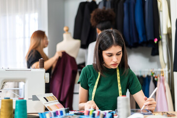 Fototapeta premium Portrait of young beautiful woman fashion designer stylish sitting and working with color samples.Attractive young girl working with colorful fabrics at fashion studio
