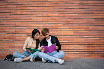 Group of young interracial diverse university students reading textbook and sitting outside a classroom under a building, engaging in a discussion together, college campus, enjoying campus recreation.