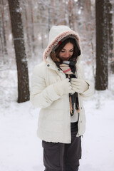 Fototapeta na wymiar Portrait of a young pretty girl in a winter snowy forest. Happy girl in winter scenery. Portret młodej, ładnej, uśmiechniętej dziewczyny w zimowym,śnieżnym lesie. 