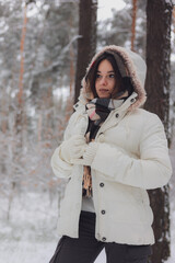 Portrait of a young pretty girl in a winter snowy forest. Happy girl in winter scenery. Portret...