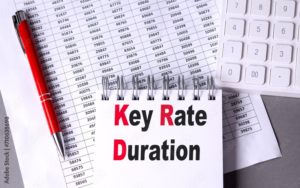 Poster key rate duration text on notebook with pen, calculator and chart on grey background