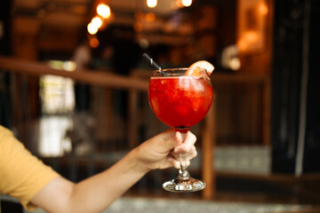 Popular bar summer ice alcoholic cocktails. Aperol Spritz and strawberry basil Margarita in glasses in woman hand at city cafe. High quality photo