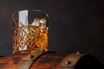 Fototapeta na wymiar Whiskey glass with ice on a rustic barrel, a classic sip