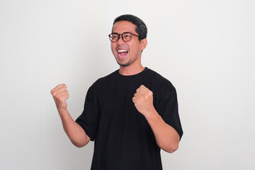 Adult Asian man looking to the right side clenching both hands showing excited expression
