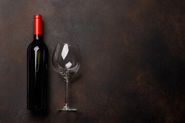 Red wine allure: Bottle and glass on rustic stone