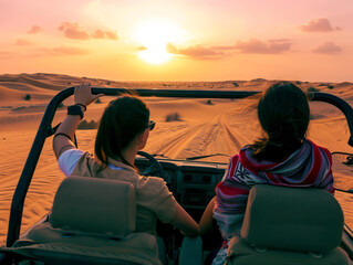 Two girls are driving a buggy car in the desert at sunset.