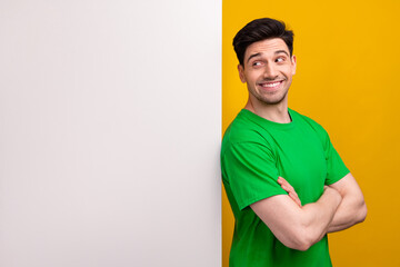 Portrait of toothy beaming guy wear stylish t-shirt look at white wall empty space palms folded isolated on yellow color background