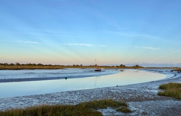 A tranquil twilight view of the River Blackwater at Maldon, Essex with beams of light shining up into the blue sky. 