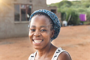 beautiful young and happy african woman in the village standing in front of the house