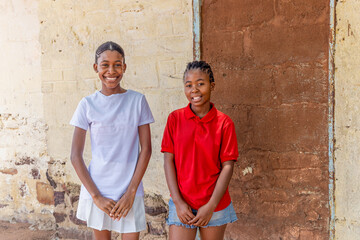 portrait young african girls with braids in the village, house in the background