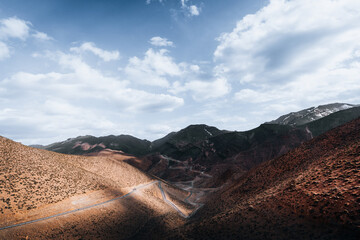 Peak Passage - Ribbons of road carve through the rugged landscape, a contrast of human passage against the eternal peaks of the Atlas Mountains.