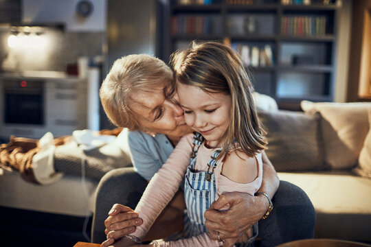 Grandmother kissing little granddaughter during movie time at home