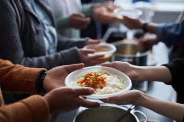 Close up of hands holding plastic plate with rice, unrecognizable volunteer helping refugees at...