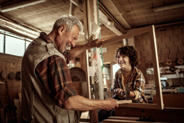 Obraz na płótnie Canvas Grandfather and grandson enjoying woodworking in a home workshop