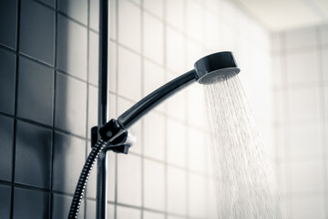 Shower head. Dark dramatic scary light. Cold water running in bathroom. Public washroom in hostel,...