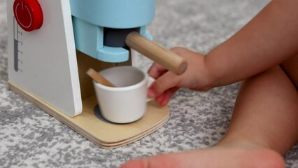 adorable baby playing with toy espresso machine. kid child putting cup, coffee, pretend to drink. coffee maker made from eco wood, safe creative roll play toys.boy sitting on floor 4k