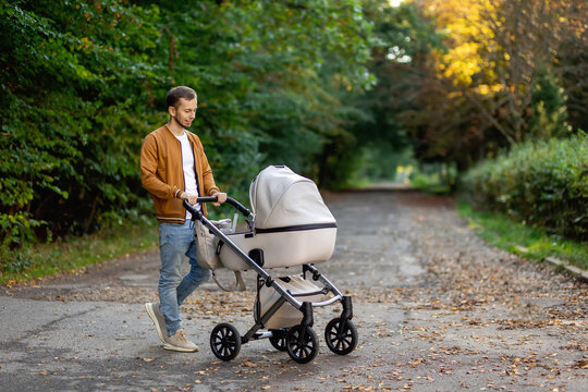 a young father walks with a stroller in the park. Walk with the child in the fresh air.