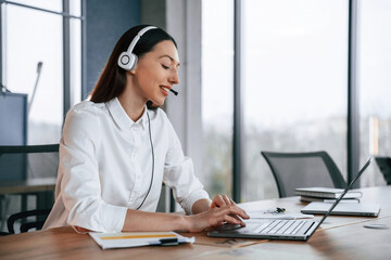 Technical support. In headphones. Businesswoman is indoors in the office