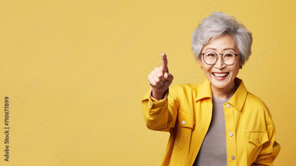 Wall mural Happy senior asian woman point her finger at copy space for promotion