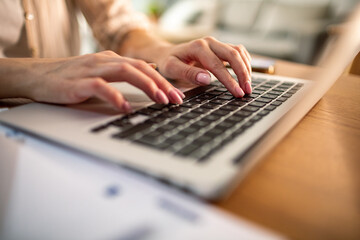 Close-up of woman's hands typing on laptop keyboard