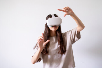 A young woman stands against a plain backdrop, engrossed in an immersive experience while wearing...