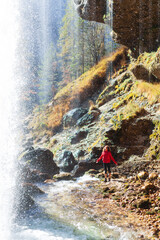 Female Mid Adult Trekker Stretching Exercises Near an Alpine Waterfall in Autumn Colors Environment