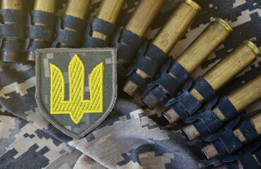 Ukrainian army symbol on machine gun belt lies on ukrainian pixeled military camouflage close up