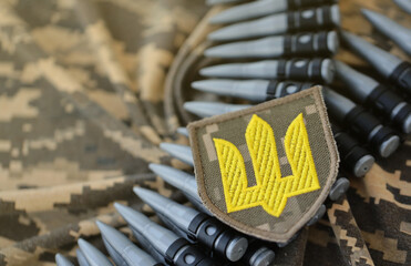 Ukrainian army symbol on machine gun belt lies on ukrainian pixeled military camouflage close up