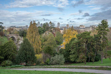 Paris, France - 11 11 2023: Park des Buttes Chaumont. View the central part of the park with footbridge, belvedere island, Temple of the Sibyl and the lake under construction due to renovation. - obrazy, fototapety, plakaty