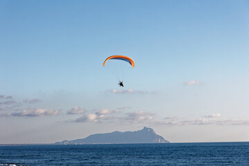 Motorized paraglider flying against the blue sky with clouds, outdoor activity, extreme sports,...
