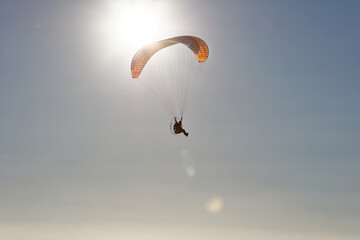Motorized paraglider flying against the blue sky with clouds, outdoor activity, extreme sports,...