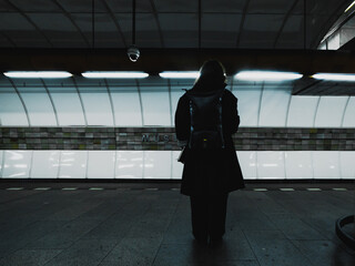woman at metro station platform seen from behind