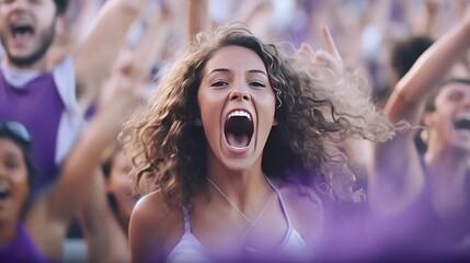 woman and group of fans celebrating and screaming supporting team in stadium seats wearing purple.Group of fans watching a sports event in the stands of a stadium - obrazy, fototapety, plakaty